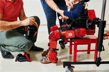 一名兒童穿戴 ATLAS 2030 外骨骼機器人坐在椅子上
